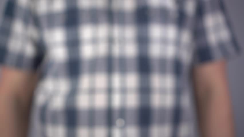 A young man draws a happy smile on the glass. A man in a plaid shirt draws with a brush and yellow paint. Close-up.