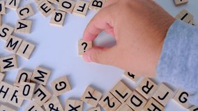 female hand close-up holds wooden alphabet blocks, makes up question marks from wooden letters on white background, dyslexia awareness, literacy problems, idea, human brain development concept - Powered by Shutterstock - Get 15% off with code: PIKWIZARD15