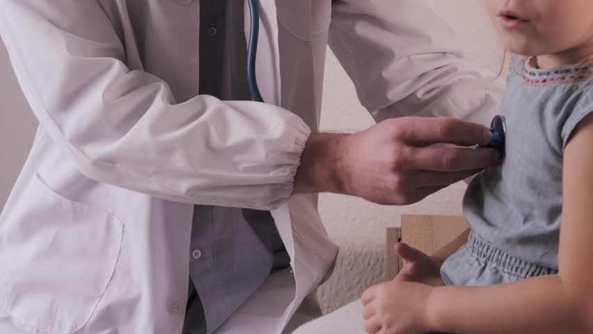 male doctor pediatrician with gadget in professional medical uniform examining patient, uses stethoscope to examine health little patient, child 3 years old, health insurance, examination, treatment Royalty-Free Stock Footage #1101828361
