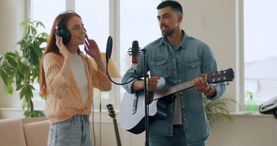 Female singer singing a song bearded handsome guy playing acoustic guitar. talented emotional woman performing vocal artist singing in recording studio. Recording for album.slow motion lifestyle hobby