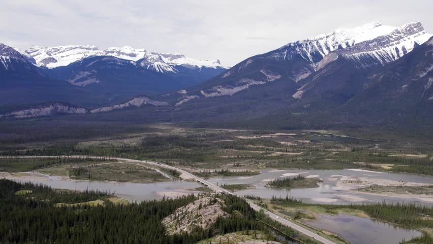 Aerial footage of Jasper Alberta with the rocky mountains in the background and the highway running beside the river