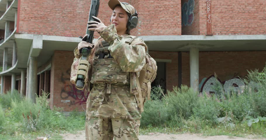 positive young woman with rifle on her shoulder is posing to camera. she is going to hunt, hunting in forest is a hobby. game with weapons slow motion