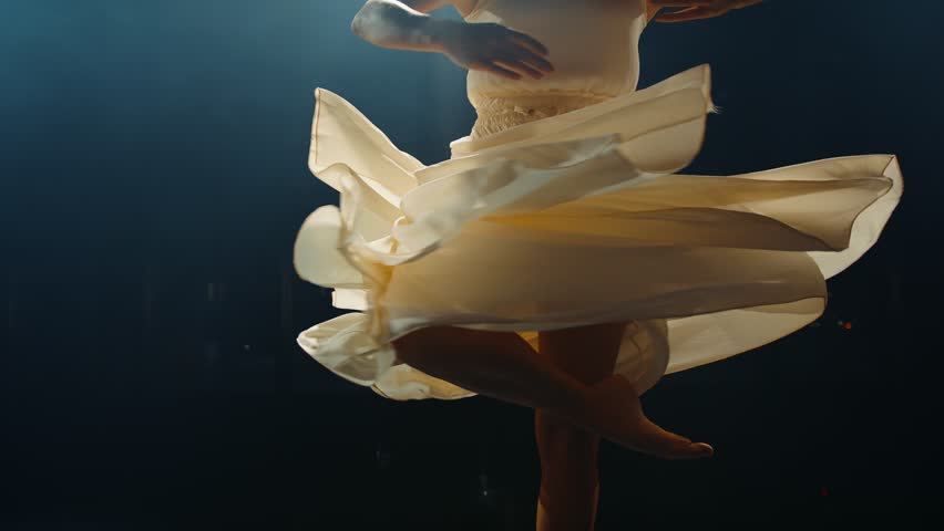 Graceful ballerina dances in light flowing dress on stage in pointlight in stage smoke. Ballet dancer performs dance elements of classical ballet Royalty-Free Stock Footage #1101832515