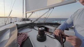 Sailor's hand on a winch of sailing boat. Man pulling ropes, winding around winches.A yacht school student learns to use a yacht winch on a ship. Sailing crew tightening up main sail winding rope