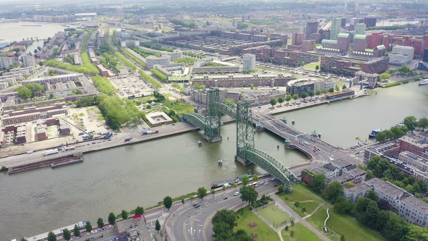 Inscription on video. Rotterdam, Netherlands. Rotterdam Bridges - Williamsburg Suspension Bridge, De Hef Drawbridge and Koninginnebrug Bridge. Multicolored text appears and disappears, Aerial View