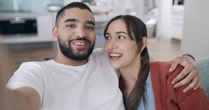 Portrait of young excited couple sharing news of engagement, showing ring on video call. Young influencer couple taking selfies and making announcement to their followers from the lounge sofa at home