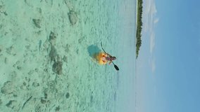 Vertical aerial view of young caucasian woman kayaking on sea in Maldives.
Aerial view of yellow kayaks in blue sea at summer. Woman on floating canoe in clear azure water.
