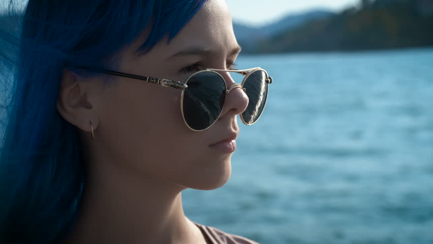 Portrait of a sad young girl. A teenager girl with blue hair takes off her glasses and is surprised.