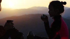 Silhouette side view of happy people - mother and daughter are spending time together. They are drinking tea at sunset, in mountains. - Powered by Shutterstock - Get 15% off with code: PIKWIZARD15