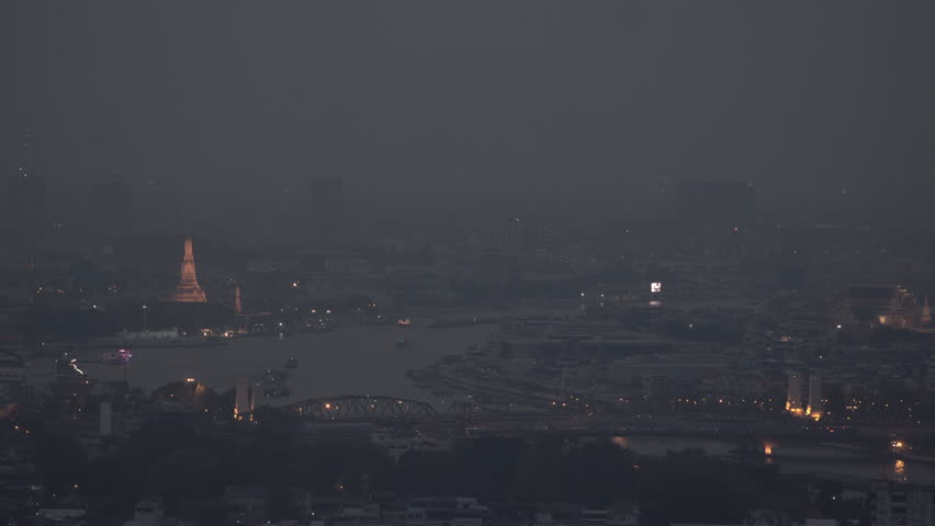 The cityscape of Bangkok is obscured by a thick blanket of dust and pollution . The heavy air pollution, filled with fine particulate matter (PM2.5), creates a hazy and oppressive atmosphere.