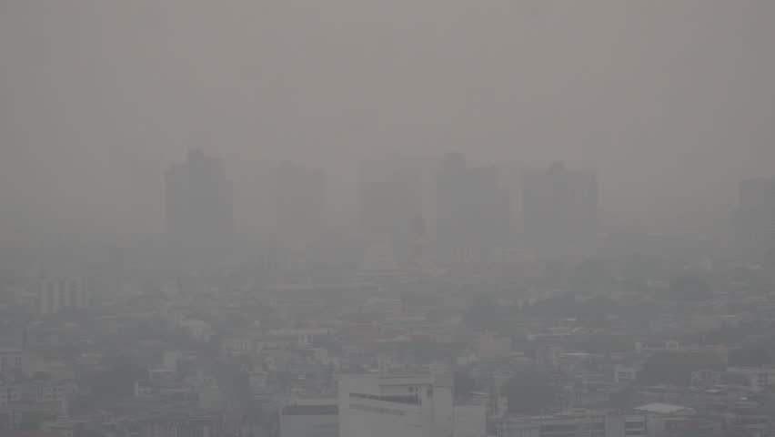 The cityscape of Bangkok is obscured by a thick blanket of dust and pollution . The heavy air pollution, filled with fine particulate matter (PM2.5), creates a hazy and oppressive atmosphere.