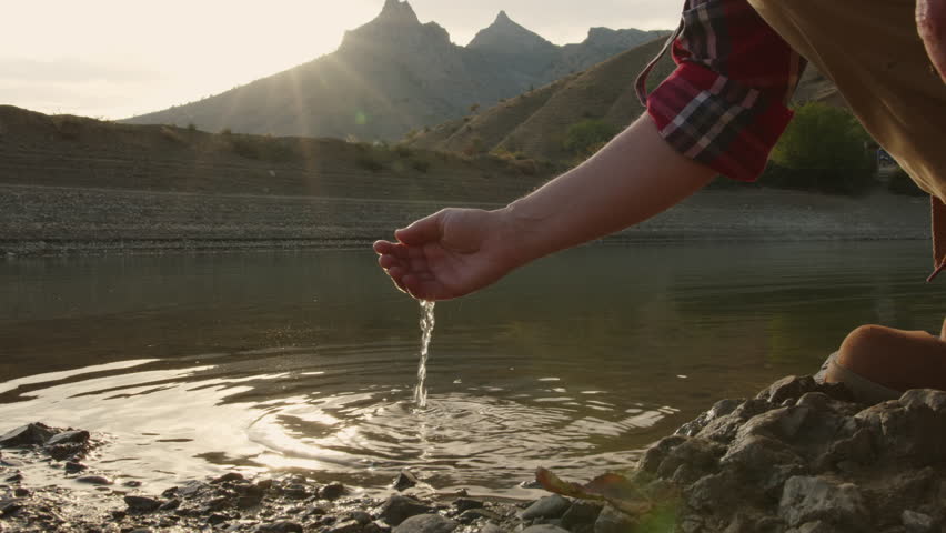 Woman hand touching water in mountain lake. | Shutterstock HD Video #1101842247