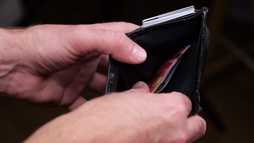 A man pulls out of his wallet and counts money in euros. View of the man