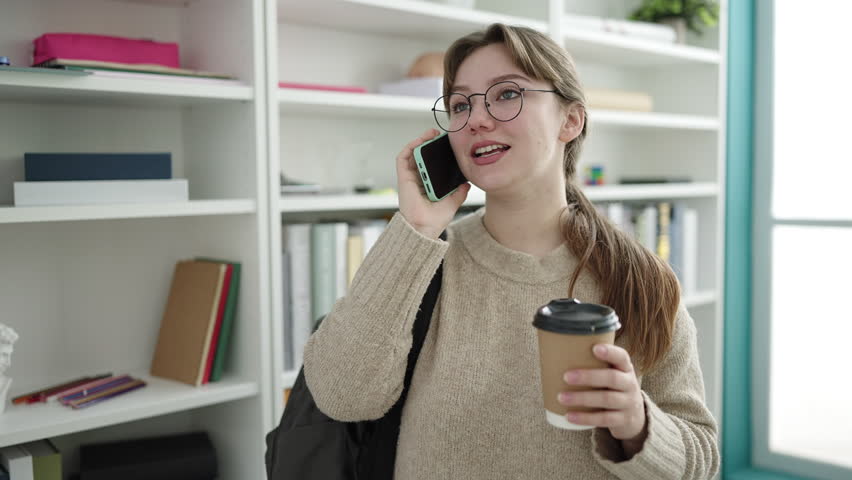 Young blonde woman student talking on smartphone drinking coffee at library university | Shutterstock HD Video #1101850779