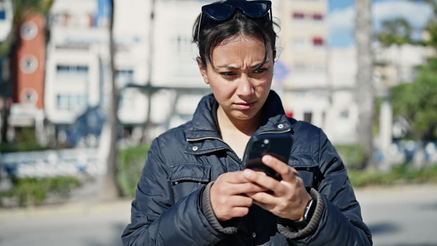 Young beautiful hispanic woman using smartphone with serious expression at street | Shutterstock HD Video #1101850897
