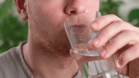 Caucasian man taking a pill and drinking a glass of water. Young man taking vitamin indoors. Health, medicine, treatment concept. - Powered by Shutterstock - Get 15% off with code: PIKWIZARD15