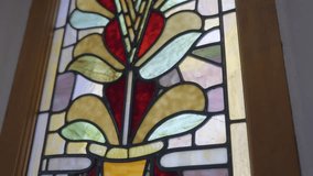 This close up video shows a colorful stained glass window with sun shining through.