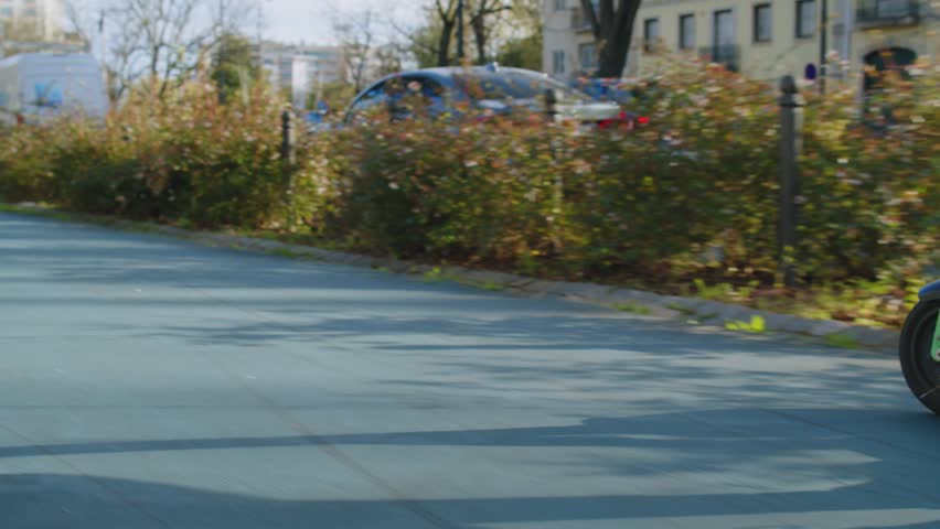 Low angle view to human legs rides on electric scooter  in  the city.  Man in a modern shoes moving on an electric scooter in the street. Ecological transport.  Soft focus. Slow motion. Back view