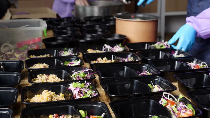 Kitchen Volunteers help feed homeless. Hot meals are prepared and packed in lunch boxes Royalty-Free Stock Footage #1101853961