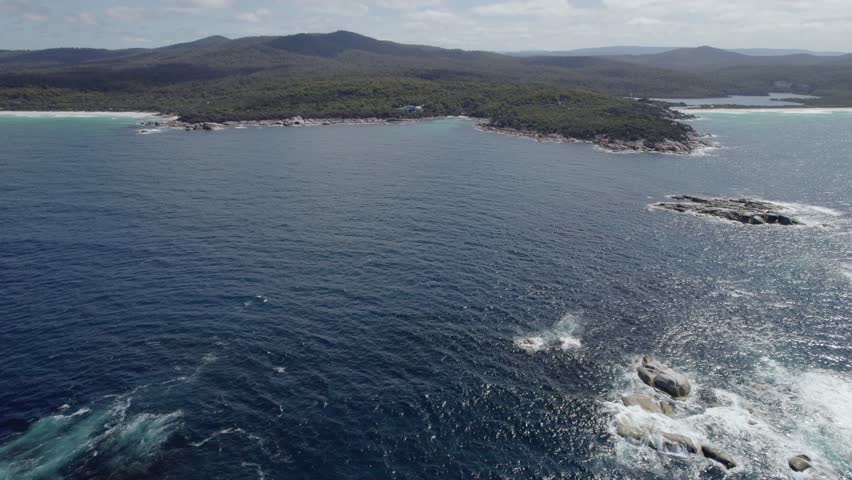 Rocky Outcrops And Foamy Waves In The Tasman Sea In Binalong Bay, Tasmania, Sloop Rock Lookout In Background. wide aerial