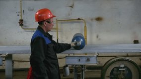 Work at the factory. Clip. A man in a helmet and a suit is working indoors with balloons.