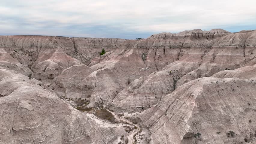Aerial shot slowly passing through valleys of ancient rock in Badlands National Park.