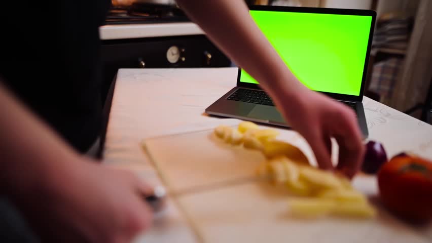 Close-up of a young woman cutting vegetables and searching for a recipe on her laptop with chroma key | Shutterstock HD Video #1101867305