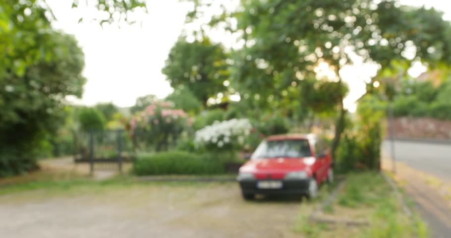 Silhouette of carefree woman walking on a sunny evening  on a French street with red small French car parked nearby