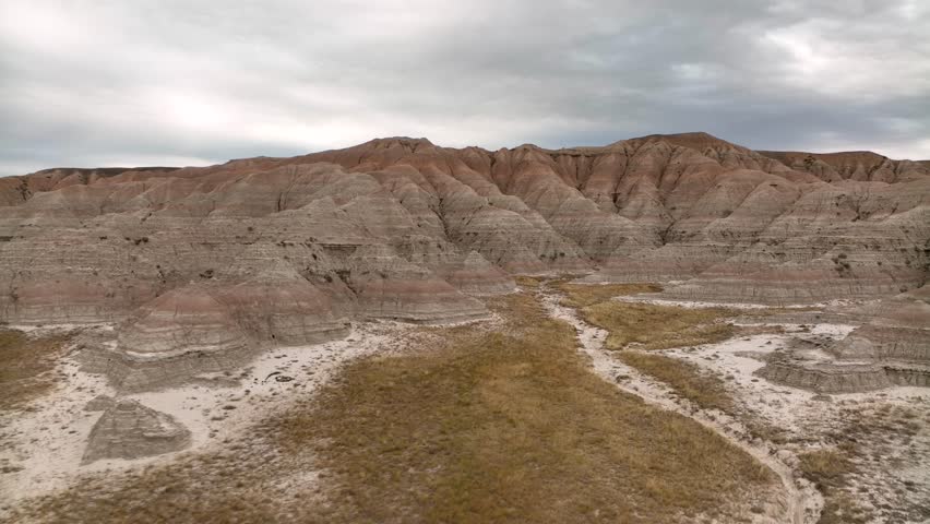 Fast moving aerial moving through the Badlands National Park among the dry and rugged canyon.