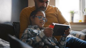 Multiracial father and son with Down syndrome playing computer game
