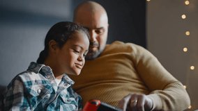 Multiracial father helping son with Down syndrome play computer game