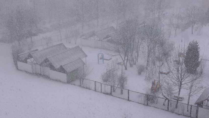 Winter snowfall, Snowstorm in the city, snowflakes fly against the background of houses