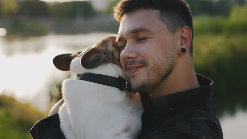 Close Up View of the Handsome Man Brooklyn Bulldog Owner Is Holding, Hugging His Favorite Pet. Man Showing Love to His Dog. People and Dogs Friendship Concept | Shutterstock HD Video #1101869193