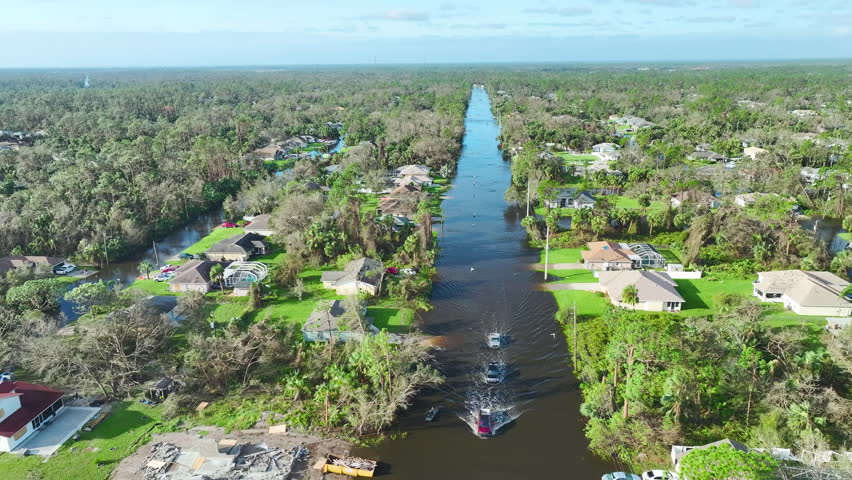 Flooded american street with moving vehicles and surrounded with water houses in Florida residential area. Consequences of hurricane Ian natural disaster