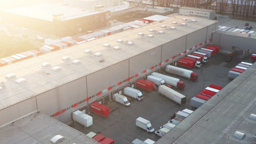Aerial view of a logistics park with warehouses. Many semi-trucks stand on ramps for unloading and loading goods | Shutterstock HD Video #1101877911
