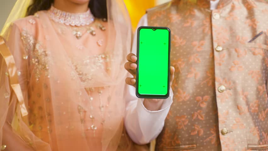 Unrecognizable shot of muslim couple showing green screen mobile phone by looking at camera at home - concept of technology,promotion and recommending. | Shutterstock HD Video #1101879901