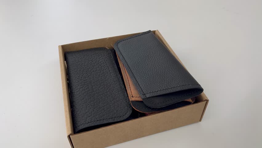 The master puts the finished leather case for glasses in a box