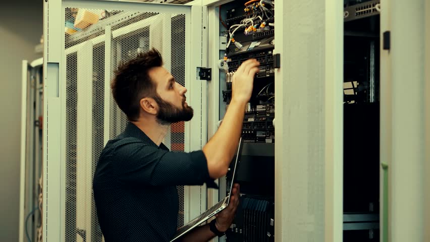 System Engineer Control Room IT Administrator. Server Engineer Work On Laptop in Data Center. Male Server IT Engineer Work Data Center. Man Work In Server Room. Male Typing On Laptop In Server Room Royalty-Free Stock Footage #1101881455