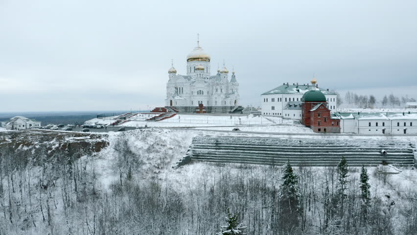 Top view of church on winter cloudy day. Clip. Snowy church with golden domes with forest. Church surrounded by forest in winter | Shutterstock HD Video #1101885195