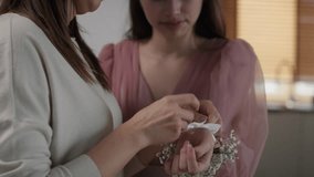 Zoom out of caucasian woman applying flower corsage on girl's wrist before prom. Shot with RED helium camera in 8K.     
