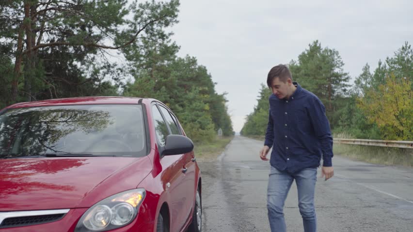 The red car stops on the side of the road due to a malfunction, a flat tire, or a broken engine. Upset driver. An emotional man near a car in which a technical malfunction occurred. Need help. 4k | Shutterstock HD Video #1101885683