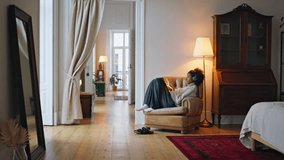 Calm girl relaxing armchair at home. Curly hair brunette listening headphones music watching tab movie at lamp light. African woman scrolling news feed at white room. Dreamy lady browsing internet - Powered by Shutterstock - Get 15% off with code: PIKWIZARD15