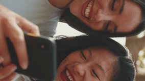 VERTICAL VIDEO: Clouse-up, young multi ethnic smiling women are watching videos on their phone. Girls laugh at picnic on summer day outdoors
