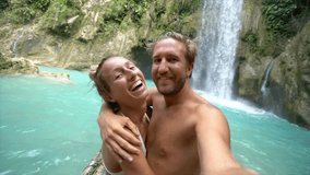 SLOW MOTION: Young couple taking selfies by stunning scenic waterfall. Couple selfie point of view in nature. Travel adventure concept. - Powered by Shutterstock - Get 15% off with code: PIKWIZARD15