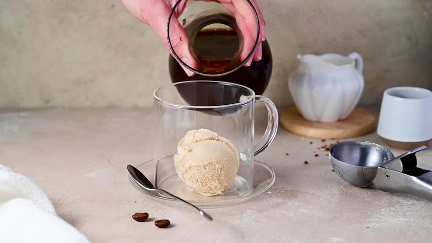 Pouring espresso coffee on ice cream scoop in glass cup Affogato Italian dessert
