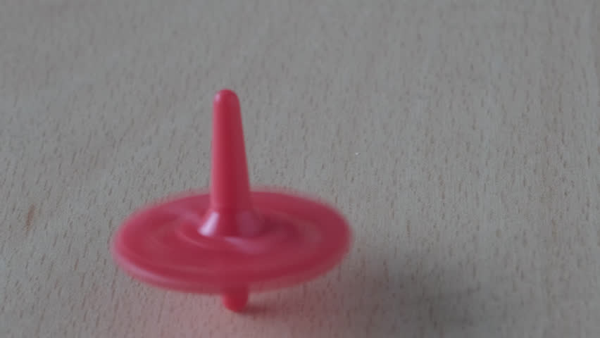Close-up of female hand spins and launches slowly colored plastic spinning top on light wooden table, concept of dizziness, loss and training of psychological balance, physical balance of body, video | Shutterstock HD Video #1101892795