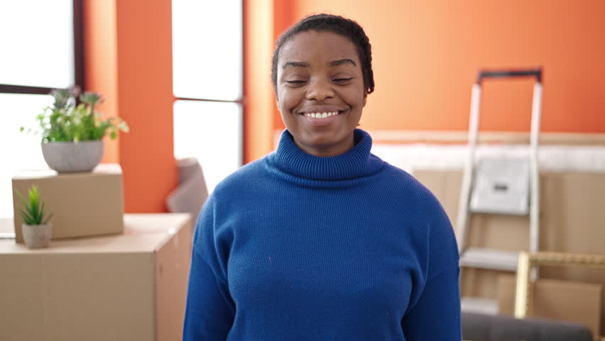 African american woman smiling confident pointing to new house keys at new home