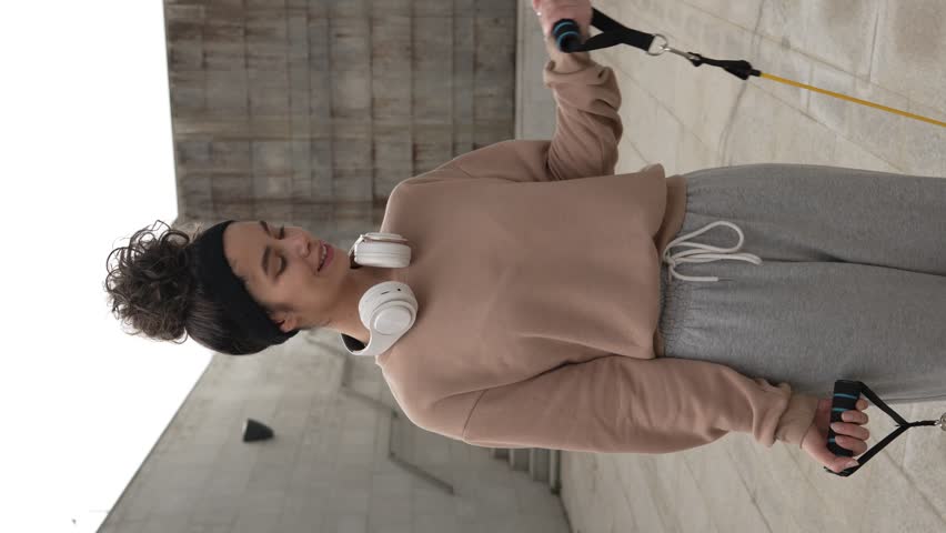 Adult caucasian woman training outdoor in the city day female athlete using rubber elastic resistance band tubes in his daily workout routine Real people health and fitness concept vertical video