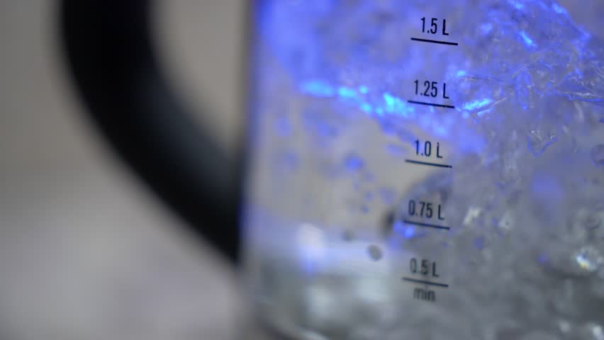 Electric glass kettle boils water. Measuring column, the amount of water. Slow motion teapot. Boiling process. Close-up, gurgling hot water, teapot lighting | Shutterstock HD Video #1101896193