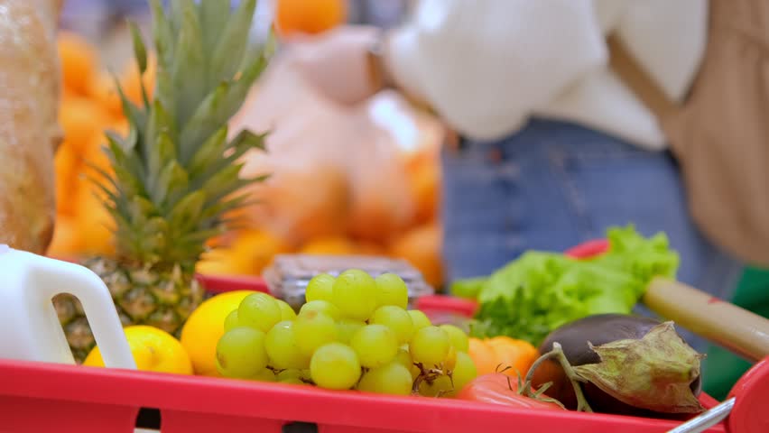 vegan products in cart 4K. Close up on woman-vegan hand choosing oranges in the supermarket in slow motion shot.